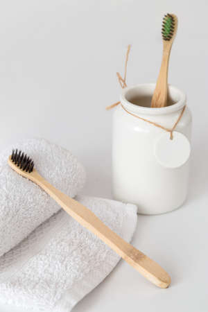 Ceramic cup with wooden toothbrush and on white towel with copy space. Ecological material and dental careの写真素材
