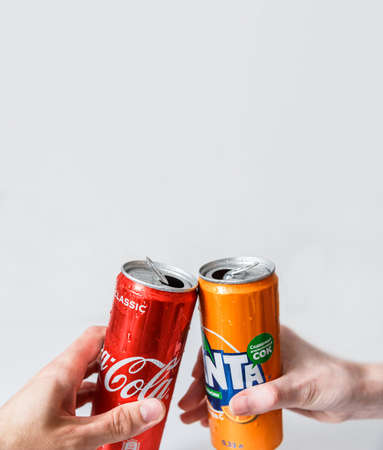 Minsk, Belarus - September 18, 2020: Two hand make clink with Coca-Cola and Fanta cans. Two drinks produced by the Coca-Cola Companyのeditorial素材