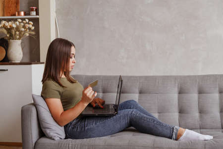 Young woman doing online payments with her credit card and laptop at home.の写真素材