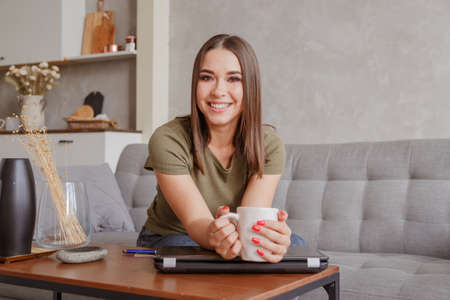 Young woman has a break with the hot beverage during working at home.の写真素材
