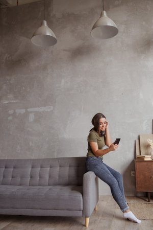 Woman with headphones while sitting on sofa in roomの写真素材