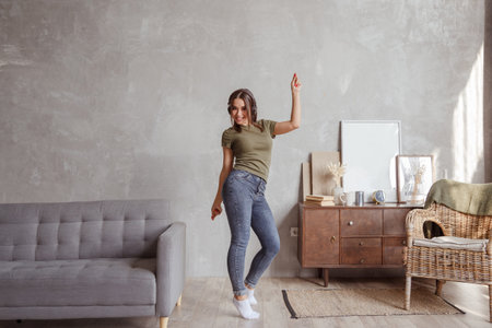 Young woman with wireless headphones dancing and listening to music at homeの写真素材