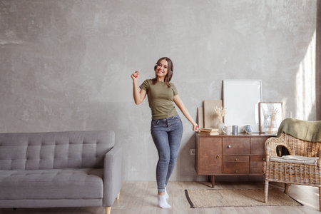 Young woman with wireless headphones dancing and listening to music at homeの写真素材