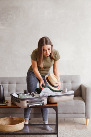 Suitcase preparation for a vacation trip after lock down. Young woman checking clothes and stuff in luggage on the sofa at home before travelの写真素材