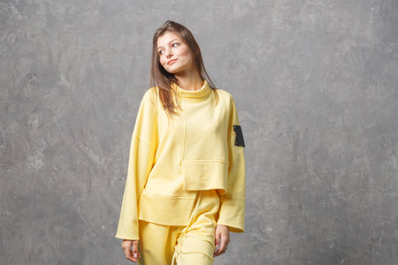 Young woman in yellow sportswear, pants and sweatshirt. Concept of fashionable sport outfit, indoors photo. Copy space.の写真素材