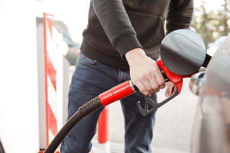 transportation and ownership concept - man pumping gasoline fuel in car at gas stationの写真素材