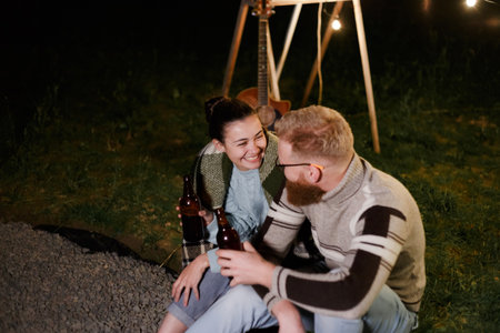 Couple have a good time together on night picnic drinking beverage from bottlesの写真素材