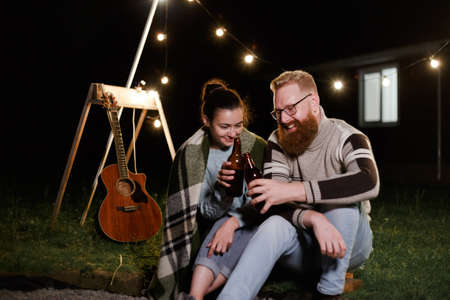 Couple have a good time together on night picnic drinking beverage from bottlesの写真素材