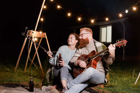 Young couple on a picnic with a guitar take a selfie or video communication with friends or relativesの写真素材