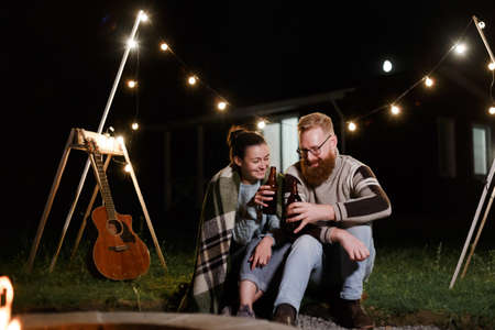 Couple have a good time together on night picnic drinking beverage from bottlesの写真素材