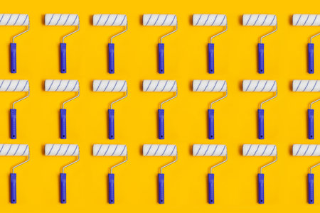 Pattern with paint roller with blue handle on yellow background. Clean roll for painting walls.の写真素材