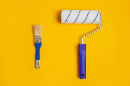 Paint roller and brush isolated on yellow. Painter tools for working with paint.の写真素材