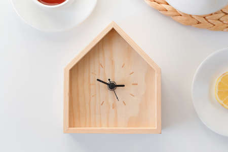 Dinner time. Wooden clock in the shape of house isolated on white background. Minimal concept. Flat lay. Top view.の写真素材