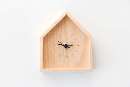 Wooden clock in the shape of house isolated on white background. Minimal concept. Flat lay. Top view.の写真素材