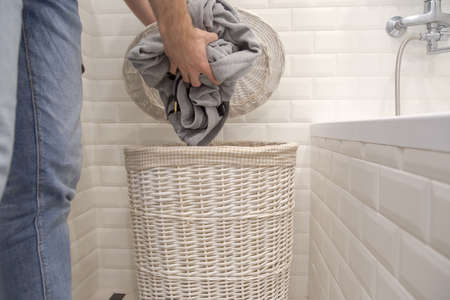 Man puts used dirty clothes in a dirty laundry basket.の写真素材
