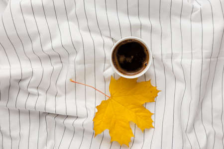 Autumn composition. Cup of coffeecup, autumn leaves on on white checkered cloth. Flat lay, top view, copy spaceの写真素材