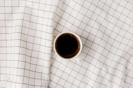 Cup of coffee cup on white checkered cloth background. Flat lay, top view, copy space. Minimal style conceptの写真素材