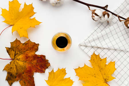 Autumn composition. Blank greeting card mockup. Cup of coffee, colorful maple leaves. White table background. Flat lay, top view.の写真素材