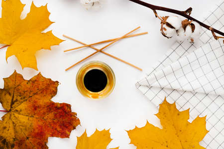 Autumn composition. Blank greeting card mockup. Cup of coffee, colorful maple leaves. White table background. Flat lay, top view.の写真素材