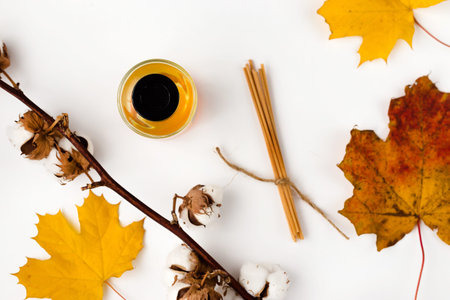 Autumn vibe composition. Blank greeting card mockup. PErfume jar, colorful maple leaves. White table...