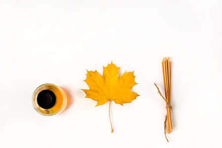 Autumn vibe composition. Blank greeting card mockup. PErfume jar, colorful maple leaves. White table background. Flat lay, top view.の写真素材