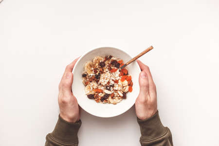 Carbohydrate healthy breakfast. Oatmeal with dried fruits on a white plate. View from aboveの写真素材