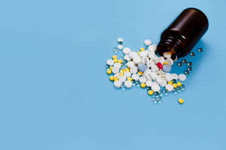 Medical bottle and medication pills spilling out on to pastel blue background. Healthcare, pharmacy, medicine conceptの写真素材