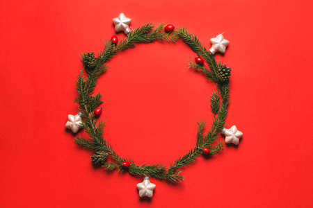 Wreath of fir, pine cones, rowan berries on red background. Winter design. Flat layの写真素材