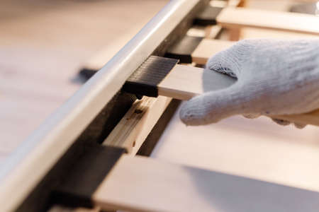 Male workers hand in glove assembling bed, connecting slats to bed frameの写真素材