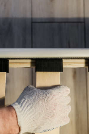 Male workers hand in glove assembling bed, connecting slats to bed frameの写真素材