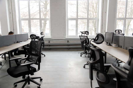 Interior of modern coworking space without people, containing tables and chairsの写真素材