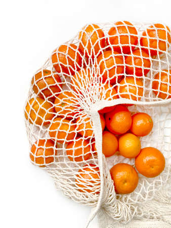 Mesh bag of fresh oranges healthy citrus fruits from on white background. Flat lay, top view.の写真素材