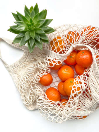 Mesh bag of fresh oranges healthy citrus fruits from on white background. Flat lay, top view.の写真素材