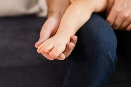 Fathers hands carefully keeping babys foot with tendernessの写真素材