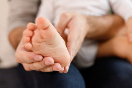 Fathers hands carefully keeping babys foot with tendernessの写真素材