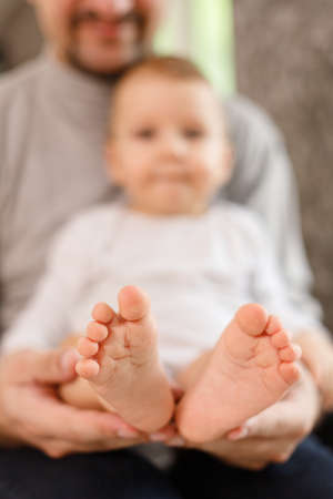 Fathers hands carefully keeping babys feet with tendernessの写真素材