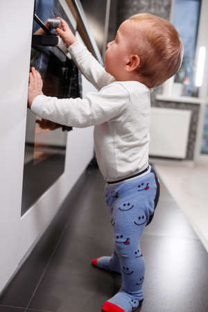 Little child playing with electric stove in the kitchenの写真素材
