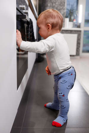 Little child playing with electric stove in the kitchenの写真素材
