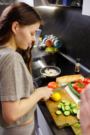Young woman cut lemon for preparing salad in kitchen, close upの写真素材