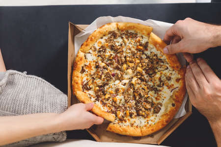 young couple eating pizza. Top view hands with pizzaの写真素材