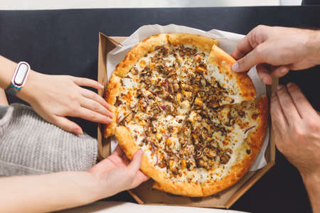 young couple eating pizza. Top view hands with pizzaの写真素材