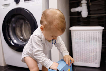 Infant boy open box with tablet for dishwasher or detergent in bathroom aloneの写真素材