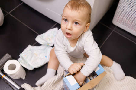 Infant boy open box with tablet for dishwasher or detergent in bathroom alone.の写真素材