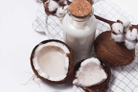 Glass bottle of milk or yogurt on dark wooden table with coconuts and coconut flakes.の写真素材