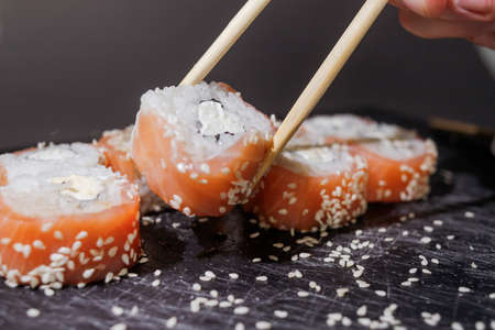Sushi rolls set served on black board on dark background.の写真素材