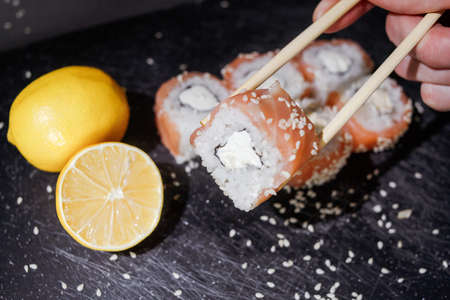 Sushi rolls set served on black board on dark background.の写真素材