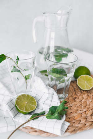 Detox water with lime fruit and mint leaves in jar and glasses.の写真素材