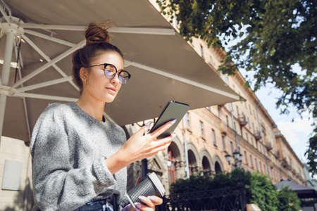 Young stylish pretty woman with smartphone at the outdoor cafeの写真素材