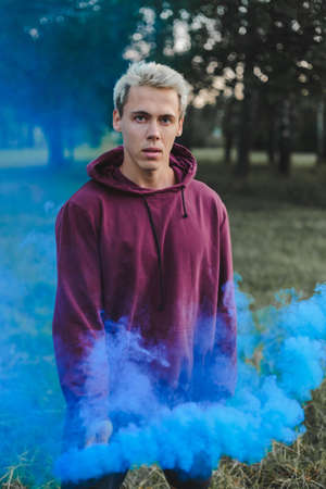 Street style man in hoodie hold hand flare with red smoke grenade bombの写真素材