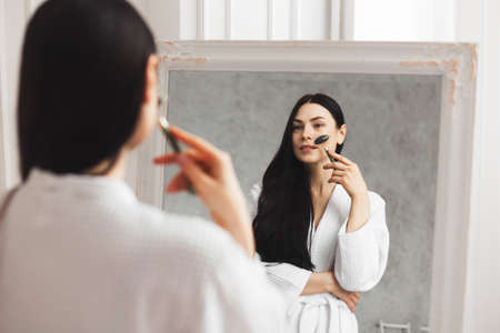 Beautiful european woman uses jade roller to massage her face. Spa self beauty treatmentの写真素材